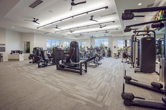 gym with ceiling fan, light colored carpet, and a wealth of natural light