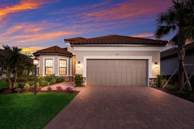 mediterranean / spanish home featuring a garage and a lawn