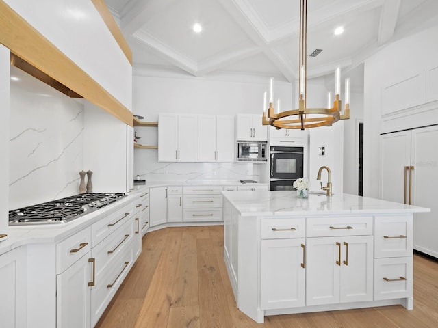 kitchen with a kitchen island with sink, built in appliances, light stone countertops, light hardwood / wood-style floors, and white cabinets