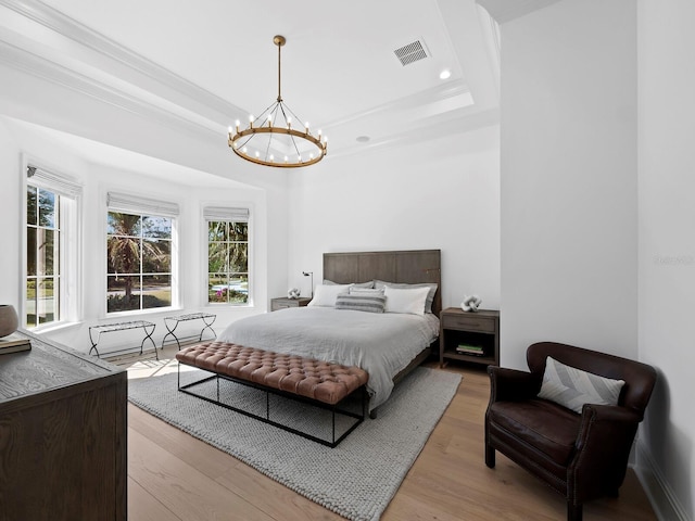 bedroom with multiple windows, a raised ceiling, a chandelier, and light hardwood / wood-style flooring