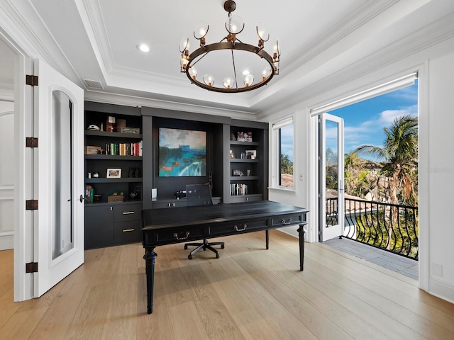 office space featuring crown molding, built in features, a raised ceiling, a chandelier, and light wood-type flooring