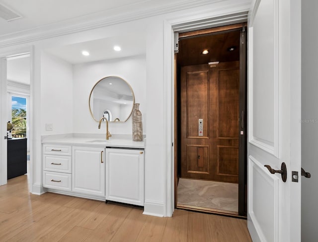 bathroom featuring crown molding, elevator, wood-type flooring, and vanity