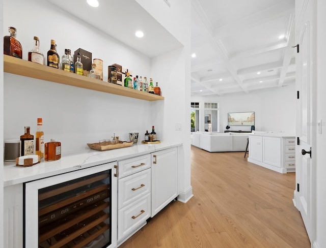 bar featuring white cabinetry, beverage cooler, coffered ceiling, light stone counters, and light hardwood / wood-style flooring