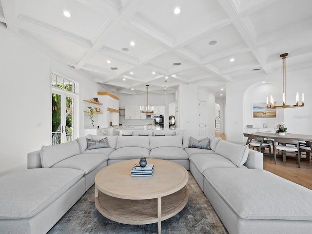 living room with an inviting chandelier, beam ceiling, dark wood-type flooring, and french doors