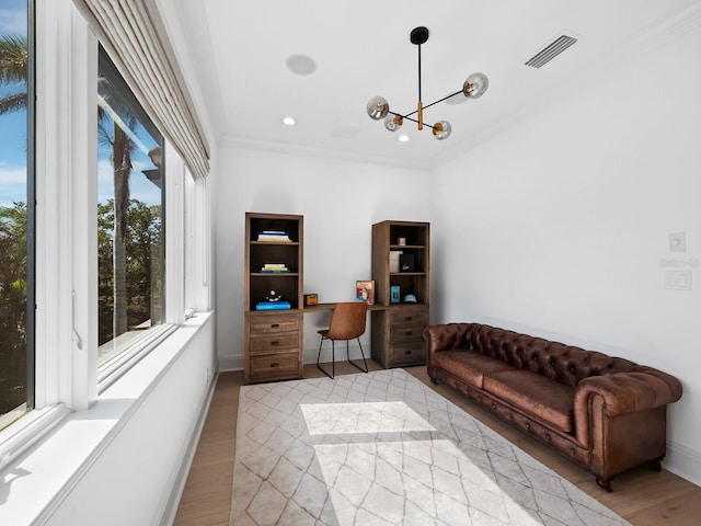 home office with a notable chandelier, crown molding, and light wood-type flooring