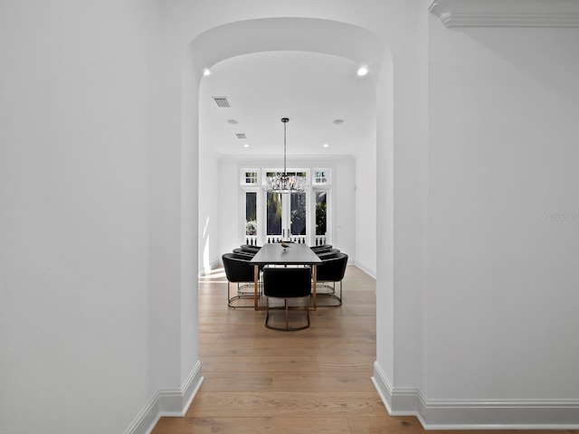 hall featuring crown molding, a chandelier, and light hardwood / wood-style flooring