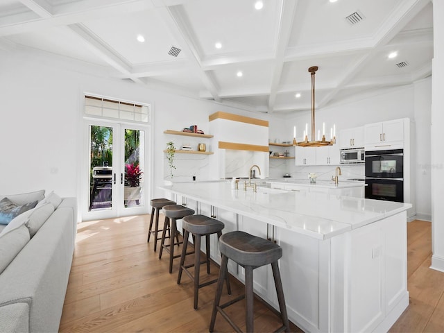 kitchen with a breakfast bar, stainless steel microwave, sink, white cabinets, and a large island