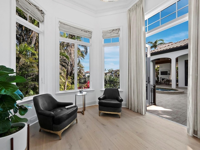 sitting room with crown molding and light hardwood / wood-style flooring