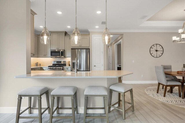 kitchen featuring stainless steel appliances, ornamental molding, hanging light fixtures, and light hardwood / wood-style floors