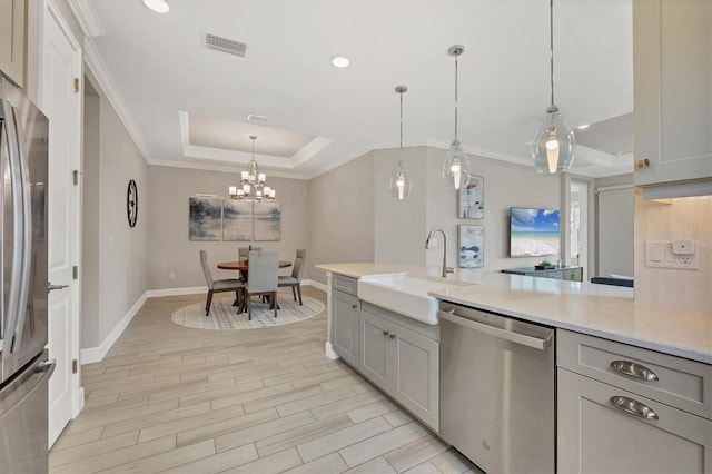 kitchen featuring sink, gray cabinetry, hanging light fixtures, stainless steel appliances, and a tray ceiling