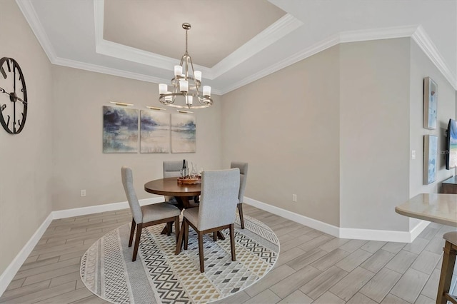 dining space with a raised ceiling, crown molding, and a chandelier