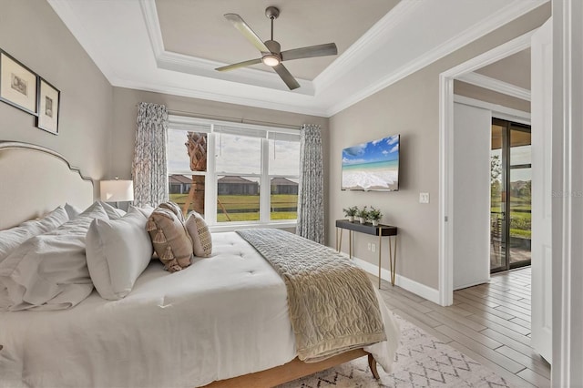 bedroom with multiple windows, a tray ceiling, and light hardwood / wood-style floors