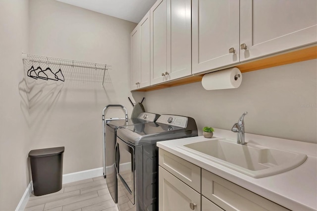 washroom featuring cabinets, sink, washer and dryer, and light hardwood / wood-style flooring