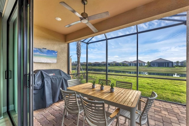 sunroom / solarium featuring ceiling fan and a water view