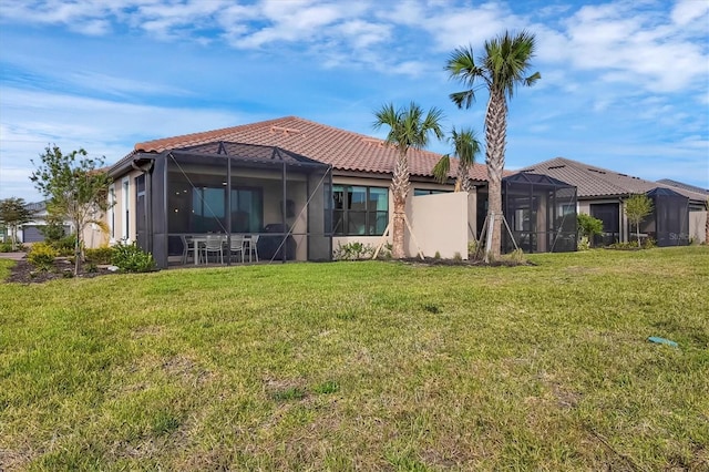 rear view of property featuring a lawn and glass enclosure