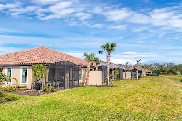 back of house featuring a lanai and a yard