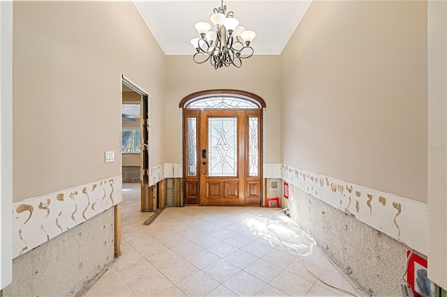 tiled foyer entrance with an inviting chandelier and ornamental molding