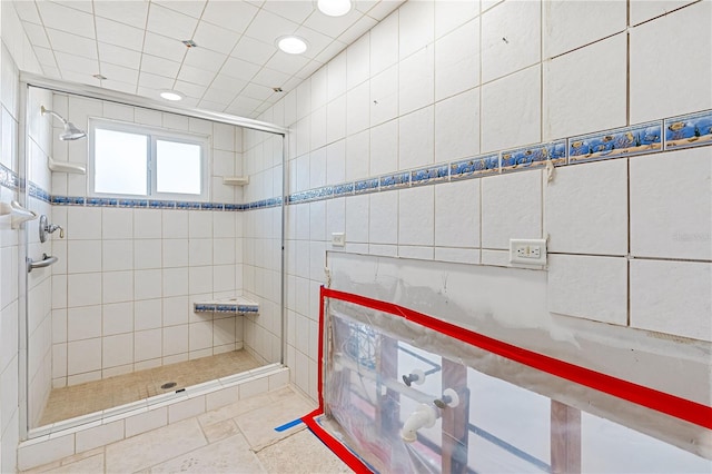 bathroom with a tile shower and tile walls