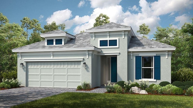 prairie-style home featuring a front lawn, decorative driveway, an attached garage, and stucco siding