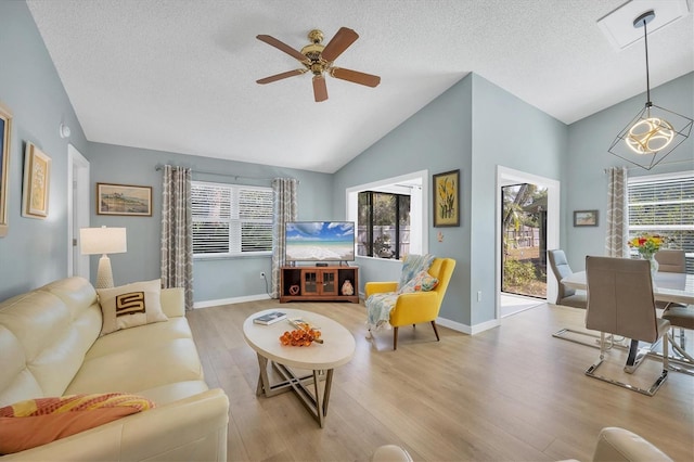 living room featuring vaulted ceiling, a textured ceiling, and light hardwood / wood-style floors