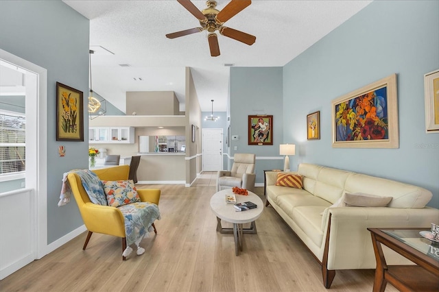 living room featuring ceiling fan, lofted ceiling, light hardwood / wood-style floors, and a textured ceiling