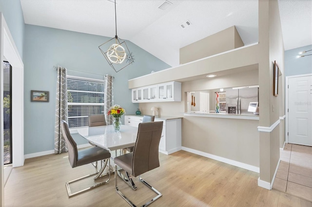 dining space featuring plenty of natural light, a chandelier, high vaulted ceiling, and light hardwood / wood-style flooring