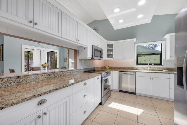 kitchen featuring stone counters, appliances with stainless steel finishes, white cabinets, decorative backsplash, and light tile patterned floors