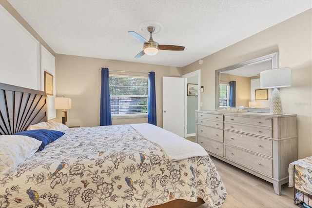 bedroom with ceiling fan, a textured ceiling, and light hardwood / wood-style floors