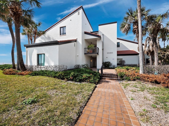 mediterranean / spanish-style home featuring a balcony and a front lawn