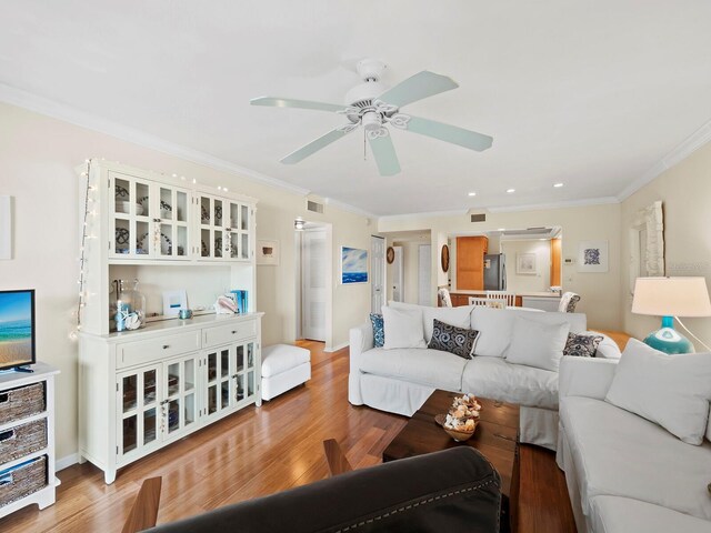 living room with hardwood / wood-style floors, crown molding, and ceiling fan