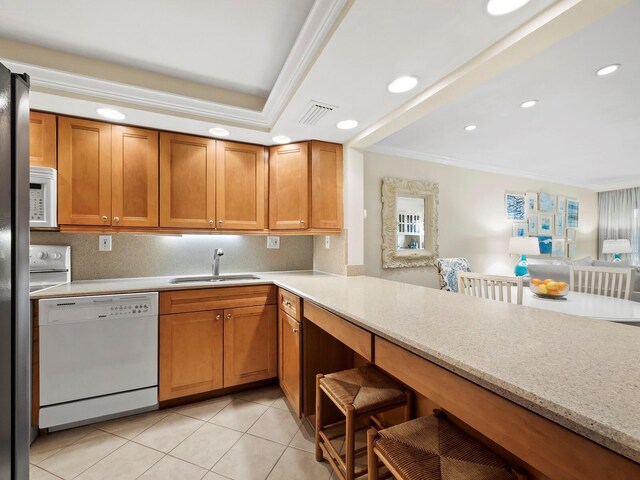 kitchen with sink, tasteful backsplash, light stone counters, kitchen peninsula, and white appliances