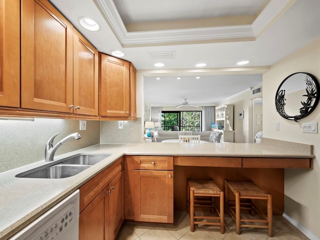 kitchen featuring light tile patterned flooring, kitchen peninsula, sink, white dishwasher, and a tray ceiling