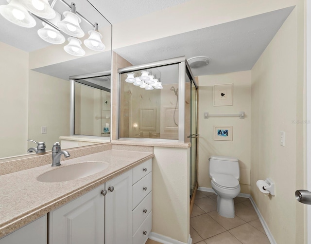 bathroom with tile patterned floors, toilet, a shower with door, and vanity