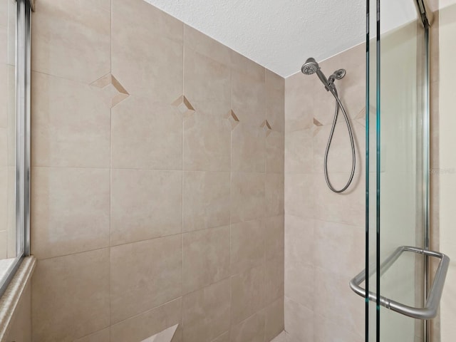 bathroom featuring a textured ceiling and tiled shower