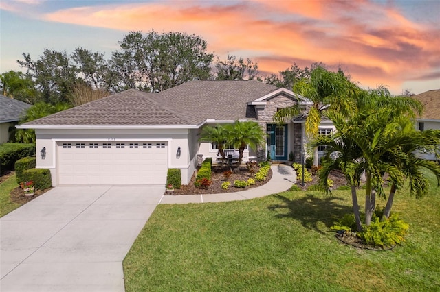 single story home featuring a garage, driveway, stone siding, a front lawn, and stucco siding