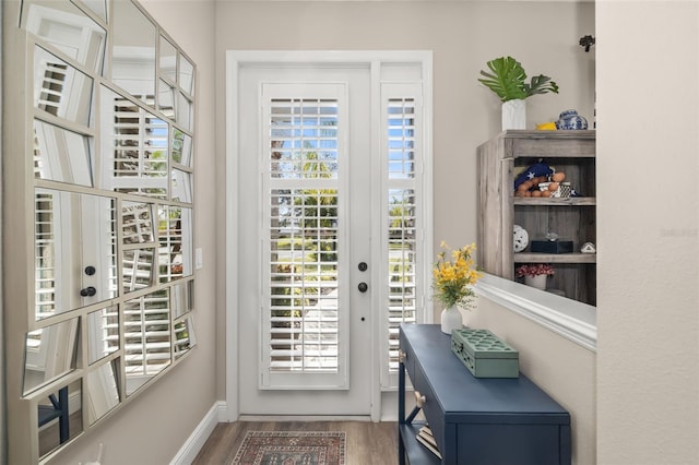 doorway with baseboards and wood finished floors