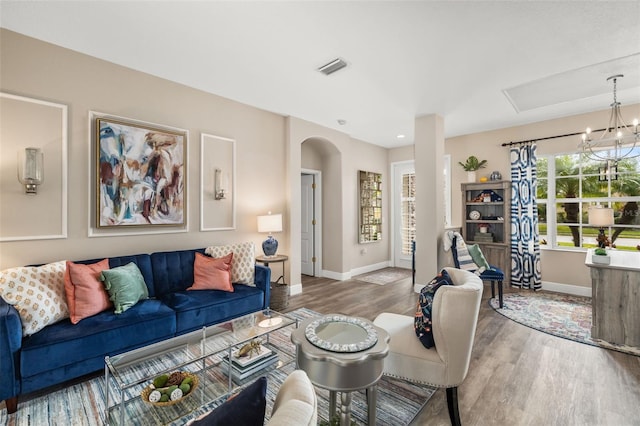 living area with arched walkways, visible vents, baseboards, and wood finished floors