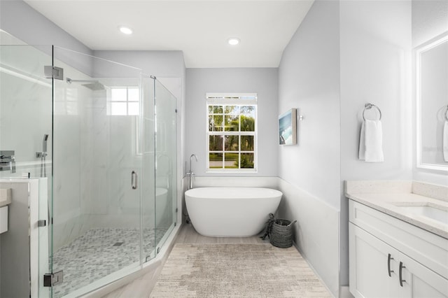 bathroom with a freestanding tub, recessed lighting, a marble finish shower, and vanity