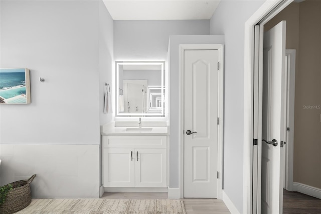 hallway featuring a sink, light wood-style flooring, and baseboards