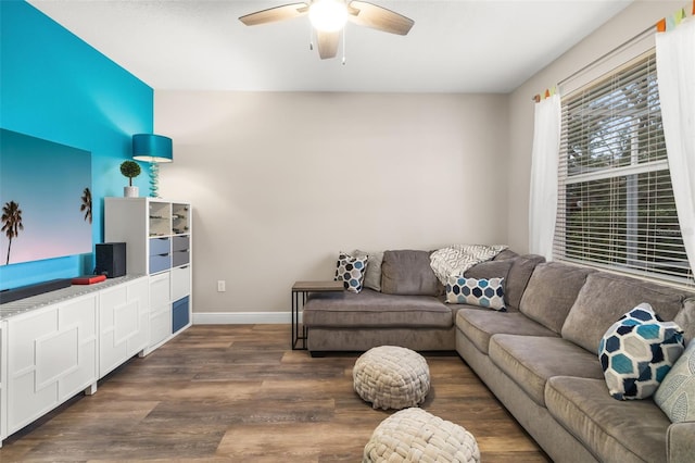 living room with a ceiling fan, baseboards, and wood finished floors