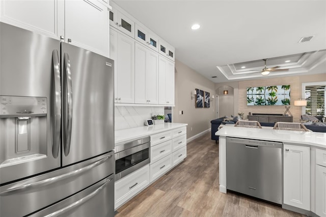 kitchen with stainless steel appliances, visible vents, open floor plan, light countertops, and a raised ceiling