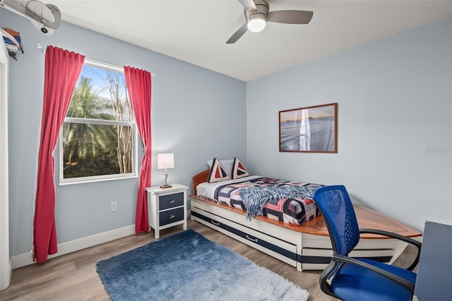 bedroom with a ceiling fan, baseboards, and wood finished floors