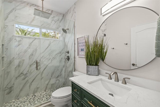 bathroom featuring toilet, a marble finish shower, and vanity