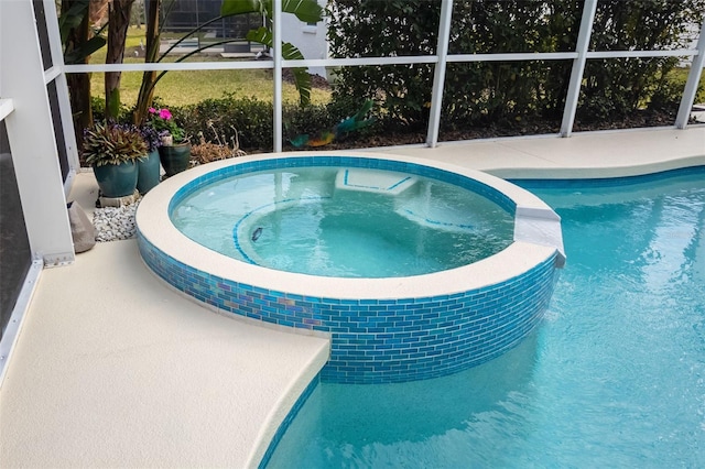 view of swimming pool featuring glass enclosure and a pool with connected hot tub