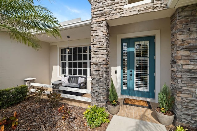 doorway to property with stone siding and stucco siding