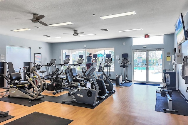 workout area featuring hardwood / wood-style flooring, ceiling fan, and a textured ceiling