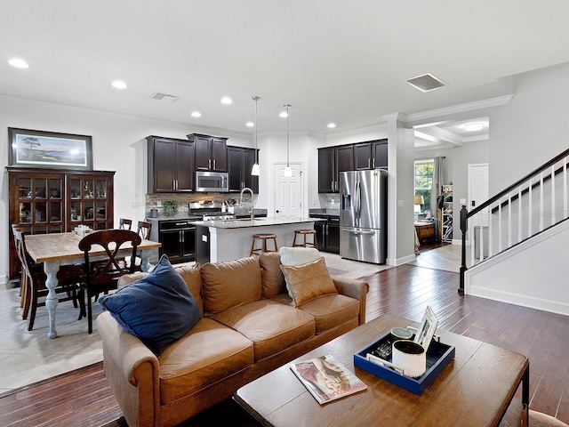 living area featuring light wood finished floors, stairs, and visible vents