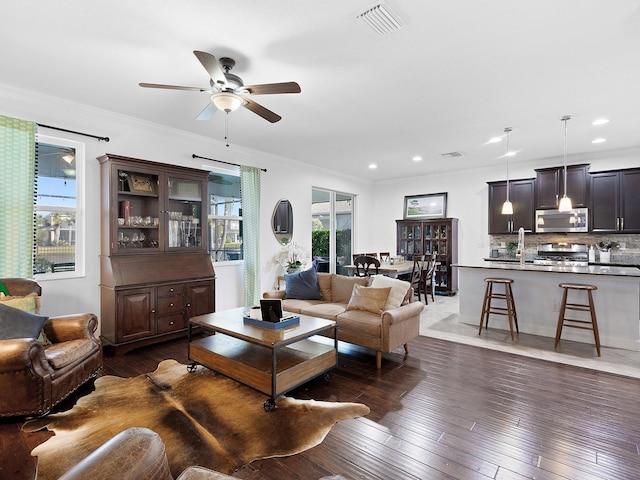 living area featuring crown molding, dark wood finished floors, recessed lighting, visible vents, and ceiling fan