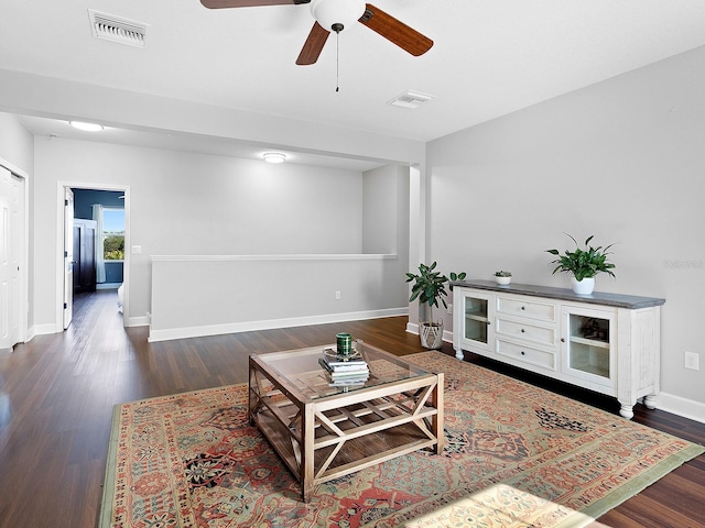 living room featuring dark wood-type flooring, visible vents, and baseboards