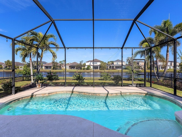 view of swimming pool featuring glass enclosure, fence, a residential view, a fenced in pool, and a patio area